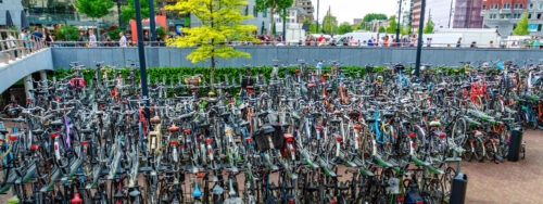 ROTTERDAM, NETHERLANDS – MAY 12, 2018: Seamless panoramic crowded bicycle park in the city. People walking on background - Starpik