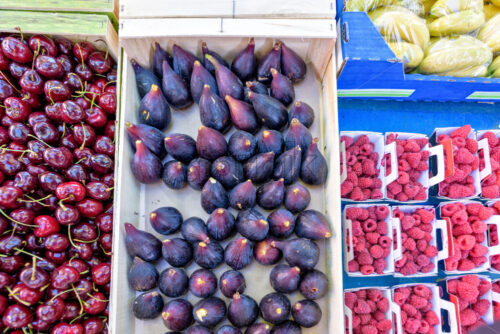 Red cherries, peaches, figs, bananas and raspberries in boxes for sale - Starpik