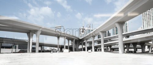 Roads and highways in Dubai, United Arab Emirates. Skyscrapers in the background. Desaturated blue sky and white sand on the ground - Starpik