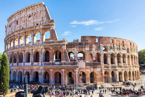 Ruins of the colosseum in Rome, walking visitors and tourists, sunny day with blue sky, Italy - Starpik