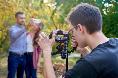 Shot of a photographer shooting a beautiful couple on the camera with a bendy tripod in a park - Starpik