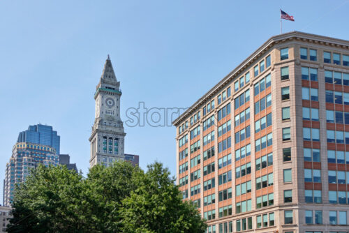 Shot of the high Custom House Tower with other modern buildings in Boston downtown, the sky behind is sunny and clear - Starpik