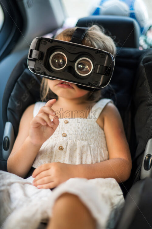 Small girl sitting in the car in VR glasses - Starpik