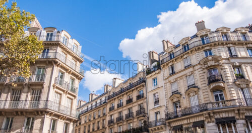 Street during midday in Paris, France. Sunny day with some clouds and bright sunlight. - Starpik