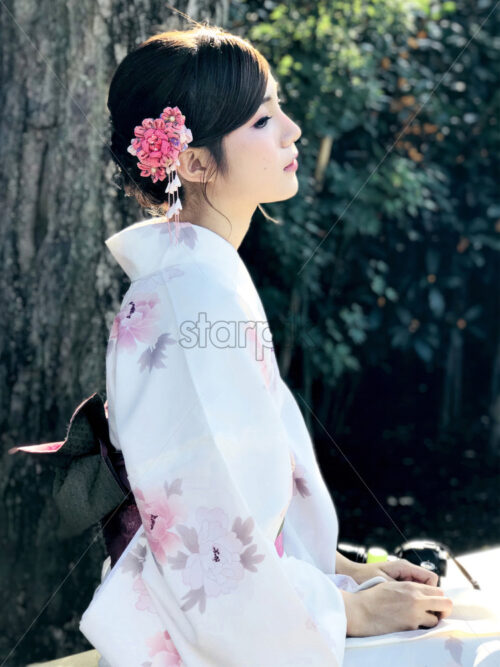 TOKYO, JAPAN – OCTOBER 9, 2017: Daylight portrait of dark hair asian female dressed in traditional clothes kimono with sakura ornaments and flowers - Starpik