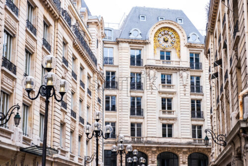 Tall French building with a giant clock. Close up shot from the distance during midday. Wonderful architecture in the center. Photo taken in Paris, France - Starpik