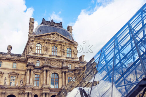 The Museum of Louvre during a cloudy day. The building is reflecting on the surface of a pyramid. Close up shot - Starpik