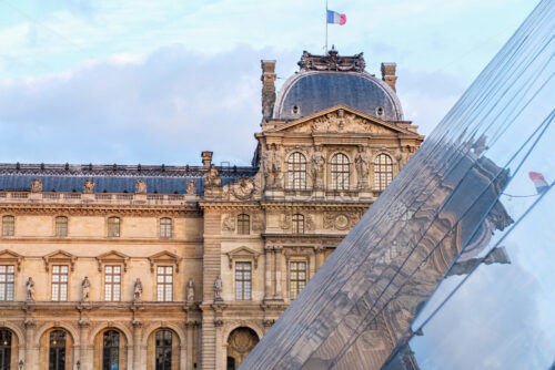 The Museum of Louvre during a cloudy day. The building is reflecting on the surface of a pyramid. Close up shot. Paris, France - Starpik