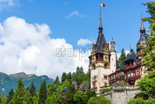 The top of Peles Castle in sunlight in Brasov. Bottom view. Blue sky with white clouds - Starpik