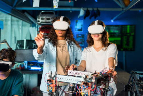 Two young women in VR glasses doing experiments in robotics in a laboratory. Robot on the table - Starpik