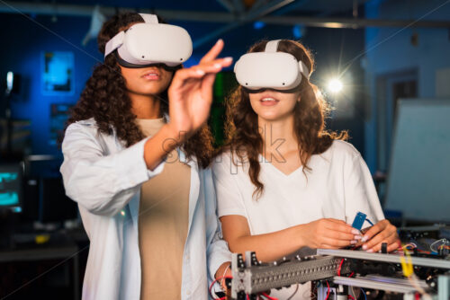 Two young women in VR glasses doing experiments in robotics in a laboratory. Robot on the table - Starpik