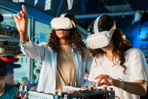 Two young women in VR glasses doing experiments in robotics in a laboratory. Robot on the table - Starpik