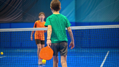 Video A boy and a girl playing pickleball on a blue, inside court - Starpik Stock