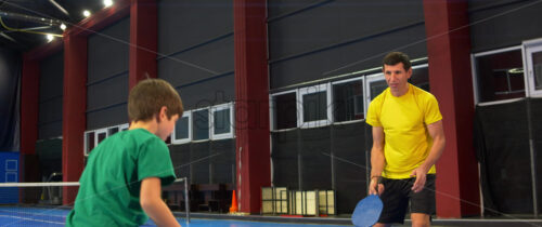 Video A boy and a girl playing pickleball on a blue, inside court - Starpik Stock