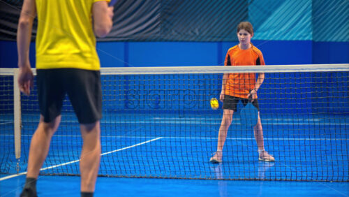 Video A man and a child playing pickleball on a blue, inside court - Starpik Stock