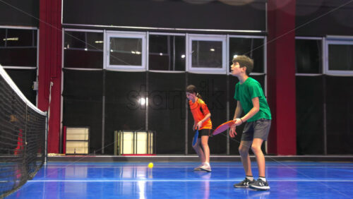 Video A man and a child training to play pickleball on a blue, inside court - Starpik Stock