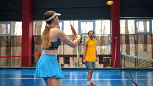 Video A man and a woman playing pickleball on a blue, inside court - Starpik