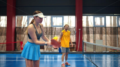 Video A man and a woman playing pickleball on a blue, inside court - Starpik