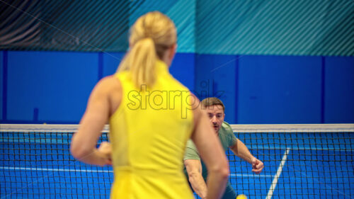 Video A man and a woman playing pickleball on a blue, inside court - Starpik