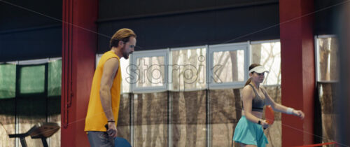 Video A man and a woman playing pickleball on a blue, inside court - Starpik