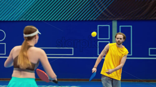 Video A man and a woman playing pickleball on a blue, inside court - Starpik