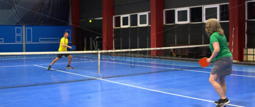 Video A man and a woman playing pickleball on a blue, inside court - Starpik Stock