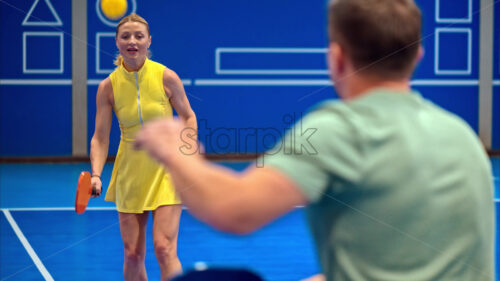 Video A man and a woman training to play pickleball on a blue, inside court - Starpik