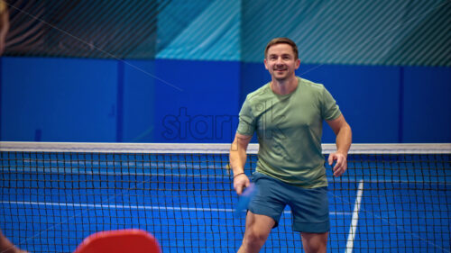 Video A man and a woman training to play pickleball on a blue, inside court - Starpik