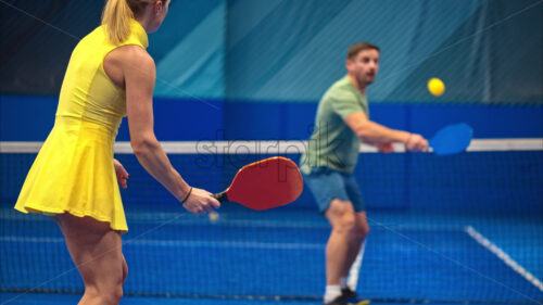 Video A man and a woman training to play pickleball on a blue, inside court - Starpik