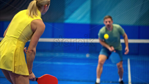 Video A man and a woman training to play pickleball on a blue, inside court - Starpik