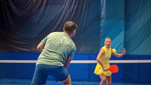 Video A man and a woman training to play pickleball on a blue, inside court - Starpik