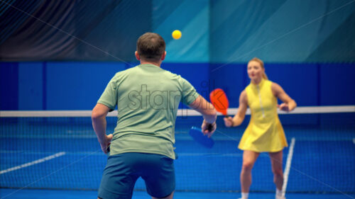 Video A man and a woman training to play pickleball on a blue, inside court - Starpik