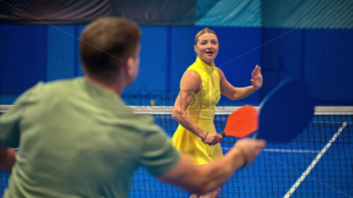 Video A man and a woman training to play pickleball on a blue, inside court - Starpik