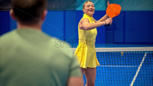 Video A man and a woman training to play pickleball on a blue, inside court - Starpik