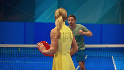 Video A man and a woman training to play pickleball on a blue, inside court - Starpik