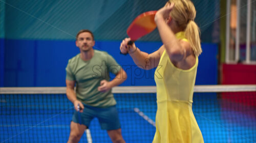 Video A man and a woman training to play pickleball on a blue, inside court - Starpik