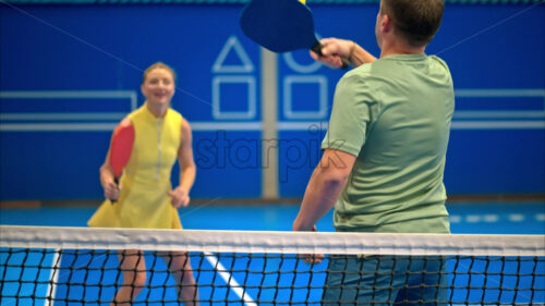 Video A man and a woman training to play pickleball on a blue, inside court - Starpik