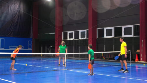 Video A man teaching his son to play pickleball on a blue, inside court - Starpik Stock