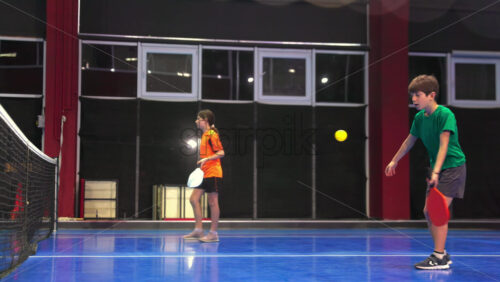 Video A man teaching his son to play pickleball on a blue, inside court - Starpik Stock