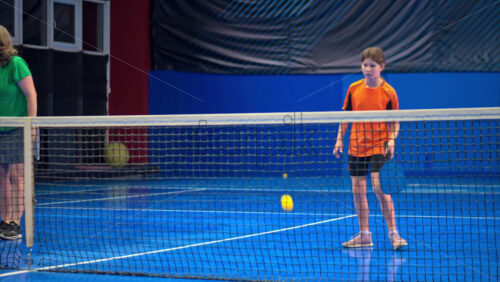 Video A woman and a child playing pickleball on a blue, inside court - Starpik Stock