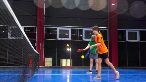 Video A woman and a child playing pickleball on a blue, inside court - Starpik Stock