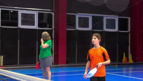 Video A woman and a child playing pickleball on a blue, inside court - Starpik Stock