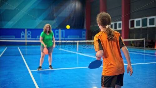 Video A woman and a child training to play pickleball on a blue, inside court - Starpik Stock