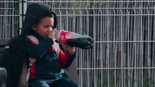 Video Nice, France – October 24, 2024: Little child drinking from a big bottle of Coca-Cola on the street - Starpik Stock