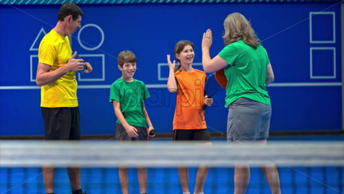 Video Two adults and two children high-fiving after playing pickleball on a blue, inside court - Starpik Stock