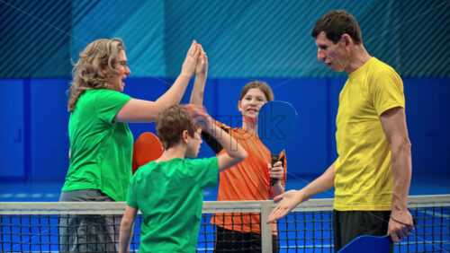 Video Two adults and two children high-fiving after playing pickleball on a blue, inside court - Starpik Stock