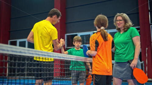 Video Two adults and two children high-fiving after playing pickleball on a blue, inside court - Starpik Stock