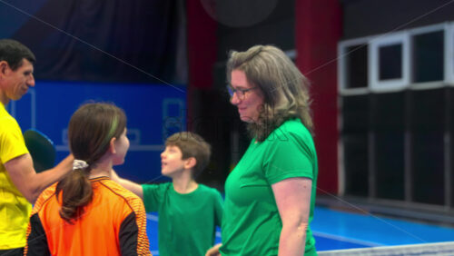 Video Two adults and two children high-fiving after playing pickleball on a blue, inside court - Starpik Stock