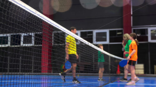 Video Two adults and two children high-fiving after playing pickleball on a blue, inside court - Starpik Stock