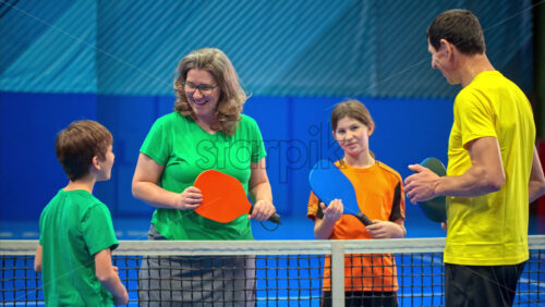 Video Two adults and two children talking after playing pickleball on a blue, inside court - Starpik Stock